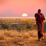 Un Masai osserva il tramonto sulla pianura del Serengeti nell'area della Tanzania